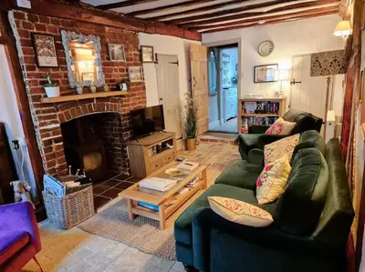 a living room with a green couch and a fireplace at Shoemakers Cottage, Halesworth in Halesworth