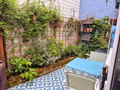 a patio with a blue table and some plants at Shoemakers Cottage, Halesworth in Halesworth
