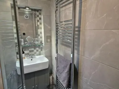 a small bathroom with a sink and a shower at Shoemakers Cottage, Halesworth in Halesworth
