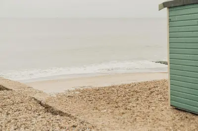 a green building on the beach near the water at Pier View Felixstowe - Sea View, 50m from the beach in Felixstowe