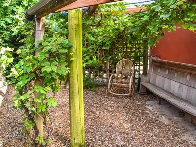 a wooden pergola with a bench and a chair at Little House On The Common in Wortham