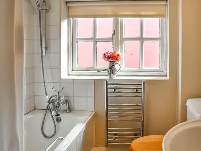 a bathroom with a bath tub and a window at Little House On The Common in Wortham