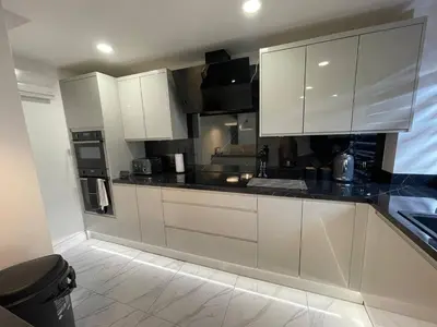a kitchen with white cabinets and black counter tops at Luxurious 2 bed home in Basildon in Basildon