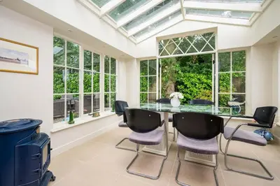 a conservatory dining room with a glass table and chairs at The Granary at Pannels Ash Farm in Sudbury