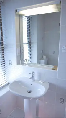 a white bathroom with a sink and a mirror at Centennial Hotel in Cambridge