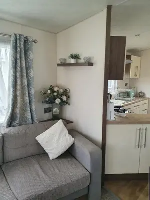 a living room with a couch and a kitchen at Kjs holiday home in Saint Osyth
