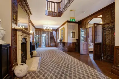 a large room with a fireplace and a staircase at Darcy West in Colchester