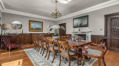 a dining room with a table and chairs and a fireplace at Darcy West in Colchester
