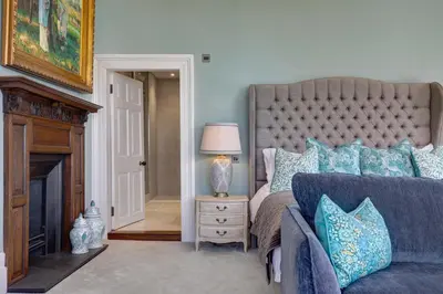 a bedroom with a large bed with blue pillows at Darcy West in Colchester