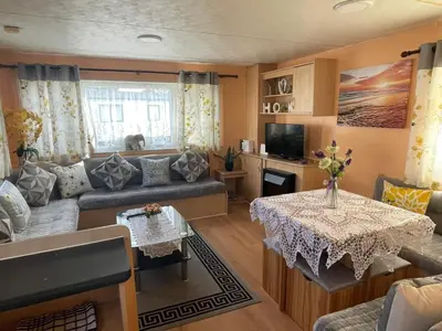 a living room with a couch and a table at Modern Caravan With Wifi At Seawick holiday park, Clacton on Sea 8 berth Large Decking in Clacton-on-Sea