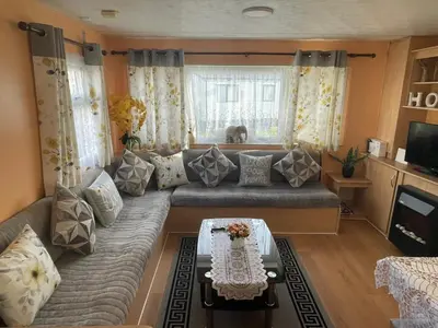a living room with a couch and a table at Modern Caravan With Wifi At Seawick holiday park, Clacton on Sea 8 berth Large Decking in Clacton-on-Sea