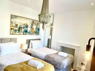 a hotel room with two beds and a chandelier at EMMANUEL HOUSE LOVELY 1 - BEDROOM APT IN HISTORICAL BUILDING CENTRAL CAMBRIDGE in Cambridge