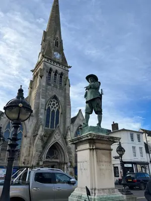 a statue in front of a church with a clock tower at Comfy, king bed families & Contractors welcome in St Ives