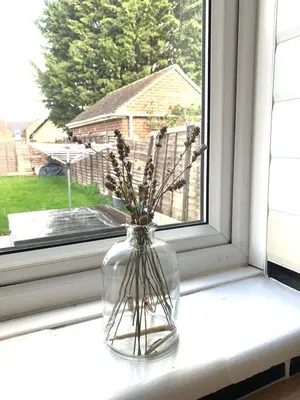 a glass vase with flowers sitting on a window sill at Comfy, king bed families & Contractors welcome in St Ives