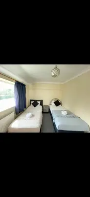 two beds in a small room with blue curtains at Comfy, king bed families & Contractors welcome in St Ives