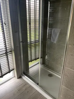 a shower with a glass door in a bathroom at Glasshouse hot tub lodge in Hengrave