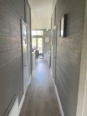 a hallway of a house with wood floors and walls at Glasshouse hot tub lodge in Hengrave