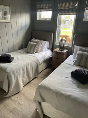 two beds in a room with two windows at Glasshouse hot tub lodge in Hengrave