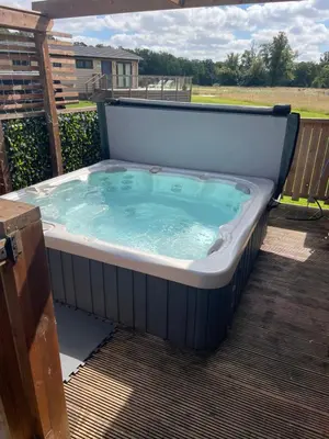 a hot tub sitting on a deck with at Glasshouse hot tub lodge in Hengrave