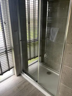 a shower with a glass door in a bathroom at Glasshouse hot tub lodge in Hengrave