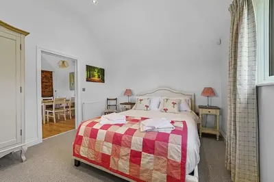 a bedroom with a bed with a checkered blanket at The Stables Rectory Farm in Halstead