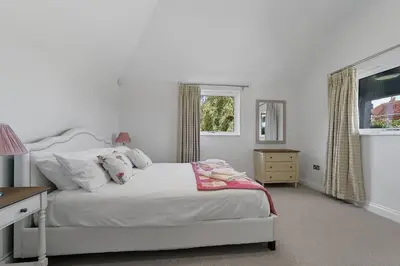 a white bedroom with a bed and a window at The Stables Rectory Farm in Halstead
