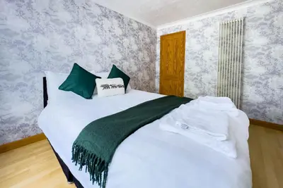a bedroom with a large white bed with green pillows at Morden holiday in Basildon