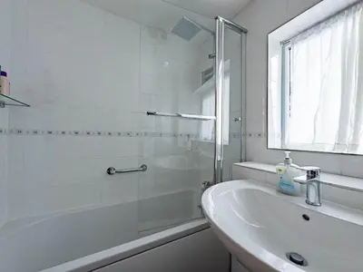 a white bathroom with a shower and a sink at Morden holiday in Basildon