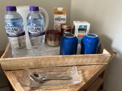 a wooden drawer with two bottles of water and a spoon at Modern, Gr Floor 1 bed, bathroom, garden & private entry with Free Parking in Cambridge