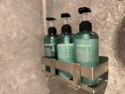 three green shampoo bottles sitting on a shelf in a bathroom at Modern, Gr Floor 1 bed, bathroom, garden & private entry with Free Parking in Cambridge