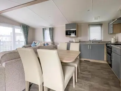 a kitchen and living room with a table and chairs at Beautiful 8 Berth Caravan With Decking At Naze Marine Park, Essex Ref 17184P in Walton-on-the-Naze