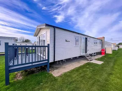 a mobile home with a blue fence in a yard at Beautiful 8 Berth Caravan With Decking At Naze Marine Park, Essex Ref 17184P in Walton-on-the-Naze
