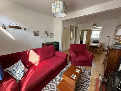 a living room with a red couch and two chairs at Beautiful Victorian house in central Cambridge in Cambridge
