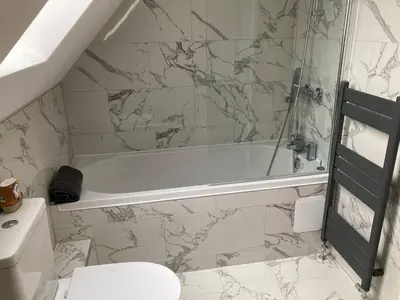 a white bathroom with a tub and a toilet at The Cottage in Birdbrook