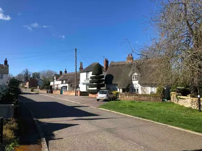 a house with a car parked on the side of a street at The Cottage in Birdbrook