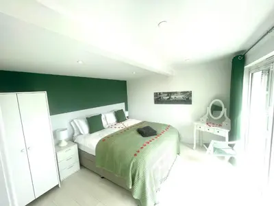 a bedroom with a bed with a green accent wall at The Hideaway-Perfect Staycation in Belchamp Saint Paul