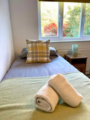 a bed with a towel on it with a window at Large 5 bed detached house near Stansted Airport with Parking for 2 vehicles! Stansted Stays in Stansted Mountfitchet
