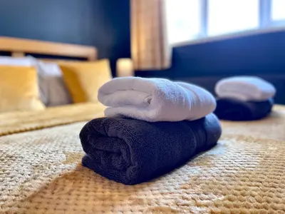 a pile of towels sitting on top of a bed at Large 5 bed detached house near Stansted Airport with Parking for 2 vehicles! Stansted Stays in Stansted Mountfitchet