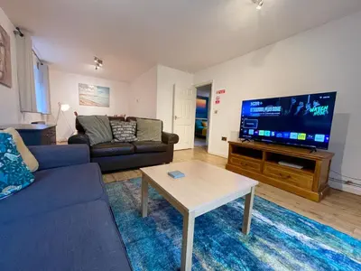 a living room with a couch and a tv at Large 5 bed detached house near Stansted Airport with Parking for 2 vehicles! Stansted Stays in Stansted Mountfitchet