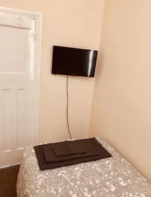 a bedroom with a bed with a flat screen tv on the wall at AC Lounge 36 (Room D) in Rochford