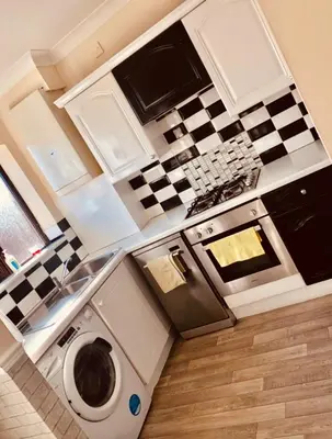 a small kitchen with a washing machine and a stove at AC Lounge 36 (Room D) in Rochford