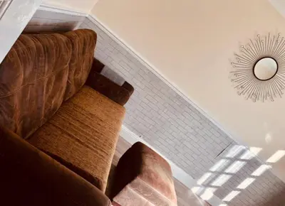a living room with a couch and a mirror at AC Lounge 36 (Room D) in Rochford