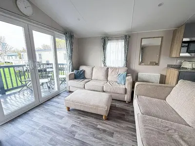 a living room with two couches and a balcony at Modern 8 Berth Caravan With Decking At Naze Marine Park, Essex Ref 17145P in Walton-on-the-Naze