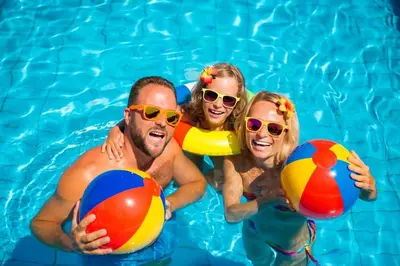 three people in a swimming pool with beach balls at Modern 8 Berth Caravan With Decking At Naze Marine Park, Essex Ref 17145P in Walton-on-the-Naze