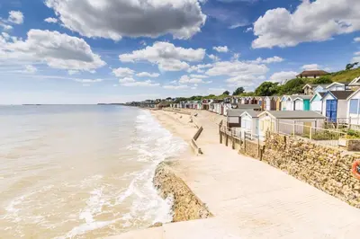 a beach with a row of houses and the ocean at Modern 8 Berth Caravan With Decking At Naze Marine Park, Essex Ref 17145P in Walton-on-the-Naze