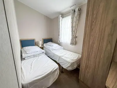 two beds in a small room with a window at Modern 8 Berth Caravan With Decking At Naze Marine Park, Essex Ref 17145P in Walton-on-the-Naze
