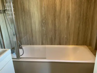 a white bath tub with a shower in a bathroom at Peaceful house ideal for dogs lovely location in Aldeburgh