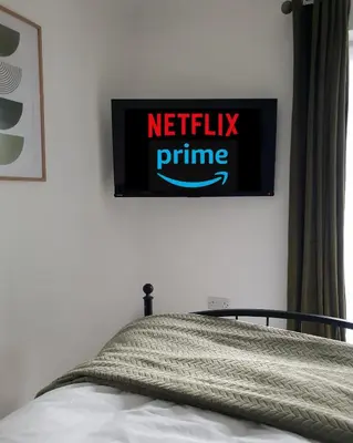 a bedroom with a netflix prime sign on the wall at Fly By - Duxford close to IWM & Wellcome Genome Campus in Duxford