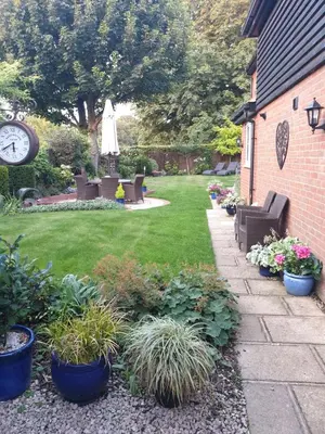 a garden with chairs and plants and a clock at Fly By - Duxford close to IWM & Wellcome Genome Campus in Duxford