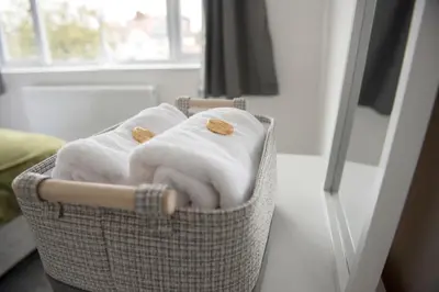 a basket filled with towels in front of a mirror at Mowbray Quarters of Cambridge in Cambridge